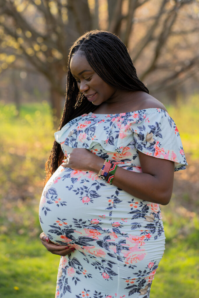 Expecting mother holding her belly and smiling down at it 