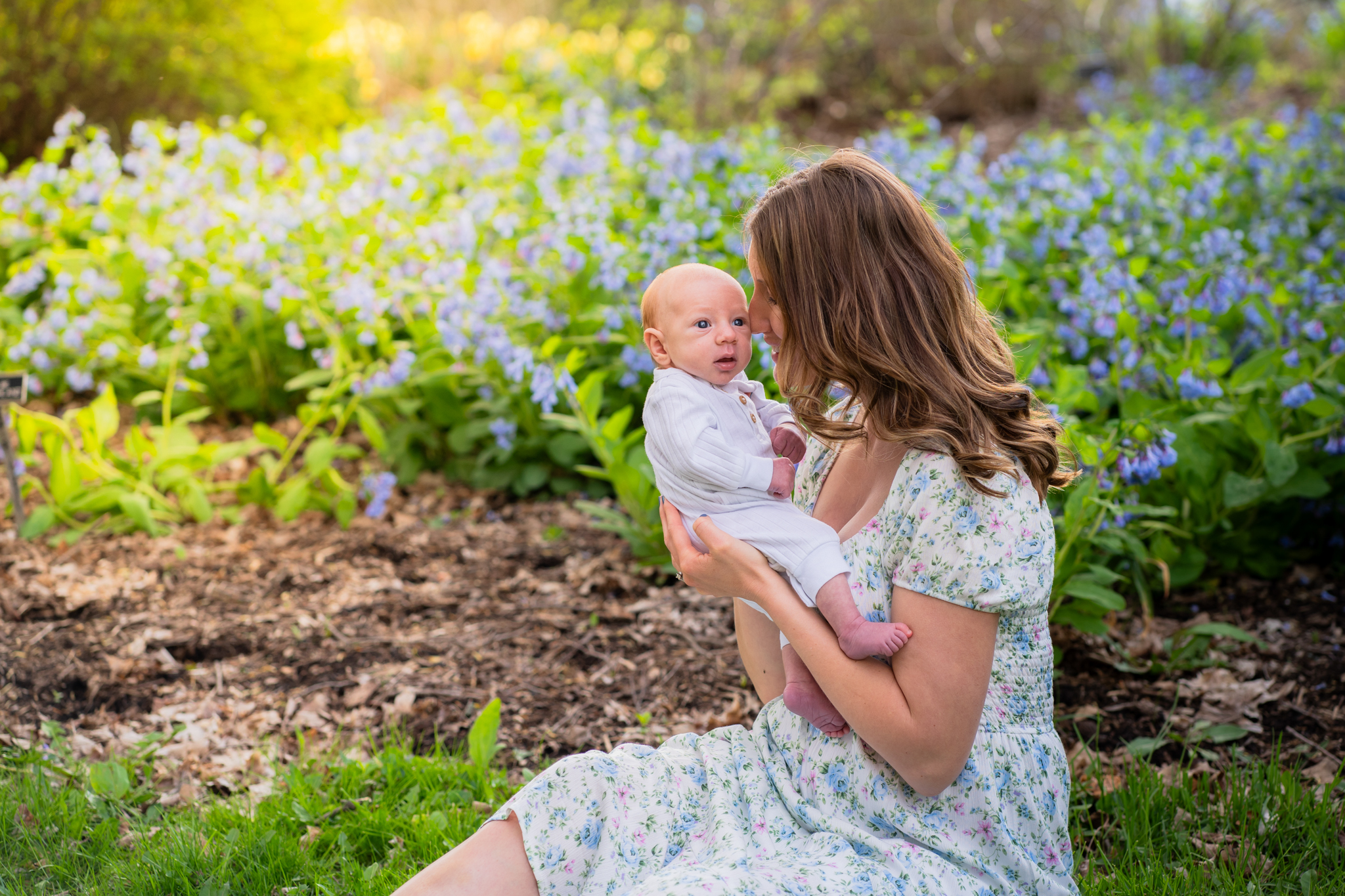 Mother holding her newborn baby while sitting in a flower garden in milwaukee wisconsin