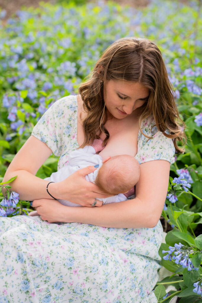 Mother breastfeeding her newborn baby in a flower garden during photography session in milwaukee wisconsin