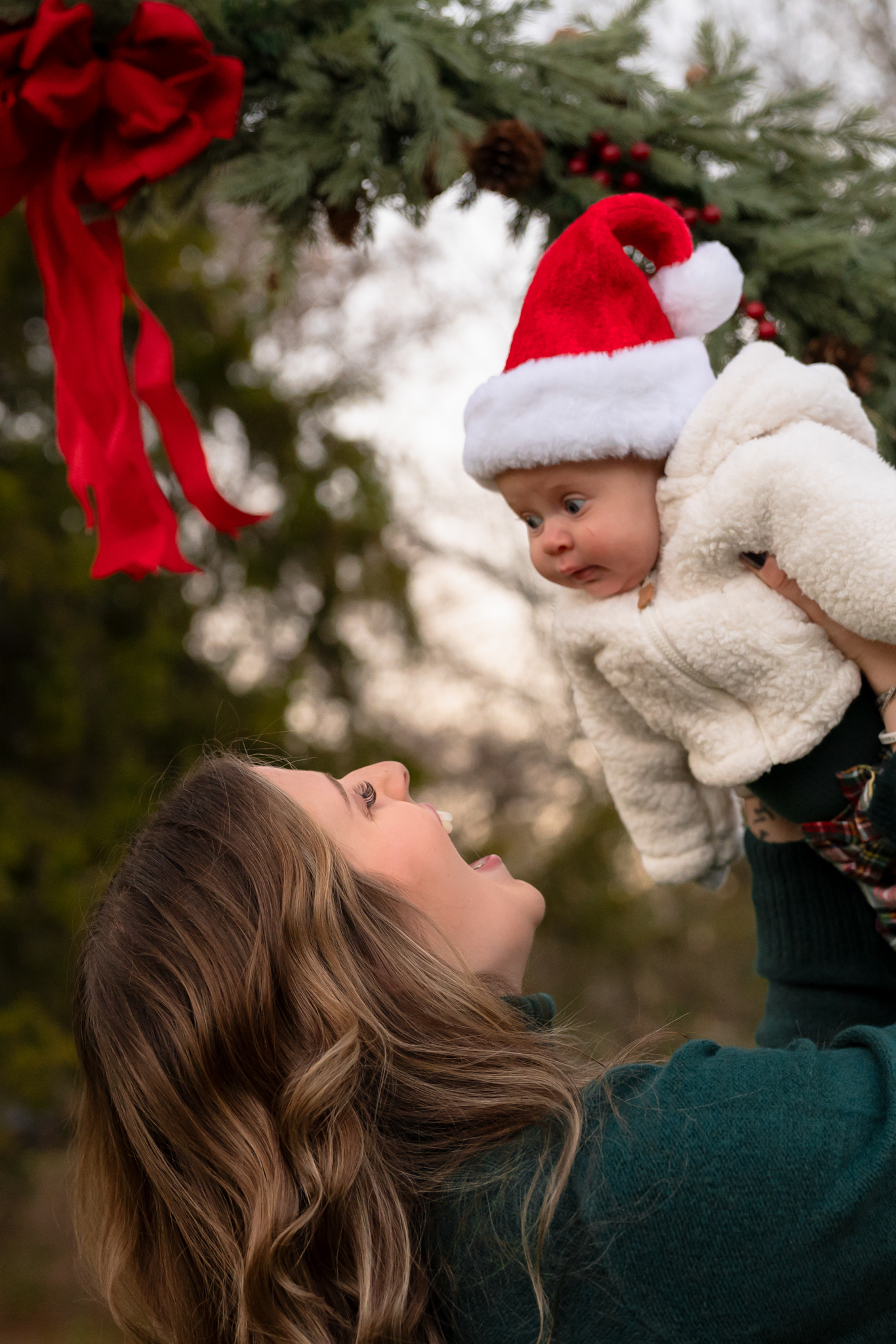 mother holding her daughter in the air and smiling at her during christmas family photography session
