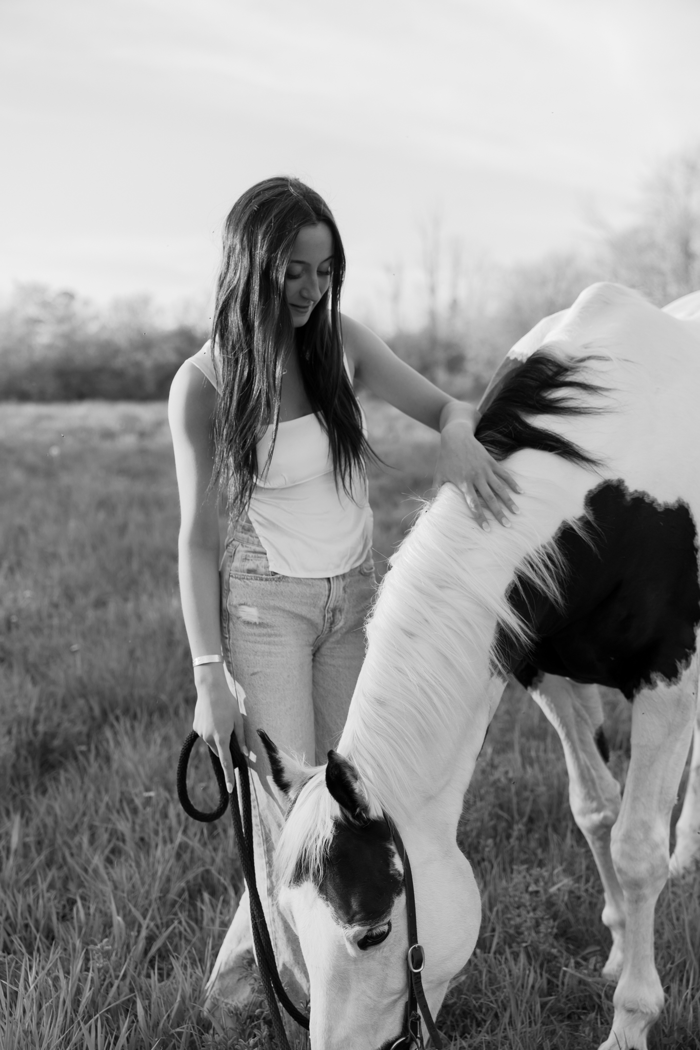 Girl holding the reigns of her horse while petting its mane during photography session in Port Washington Wisconsin