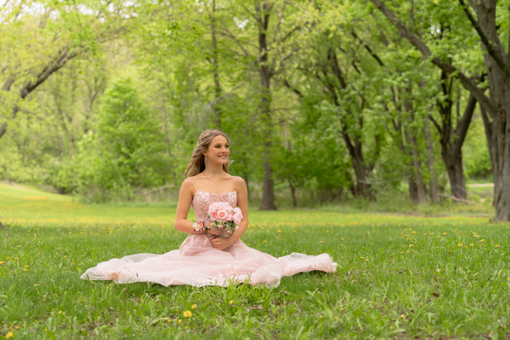 High school girl sitting on the ground in her prom dress at Pike Lake in Hartford Wisconsin