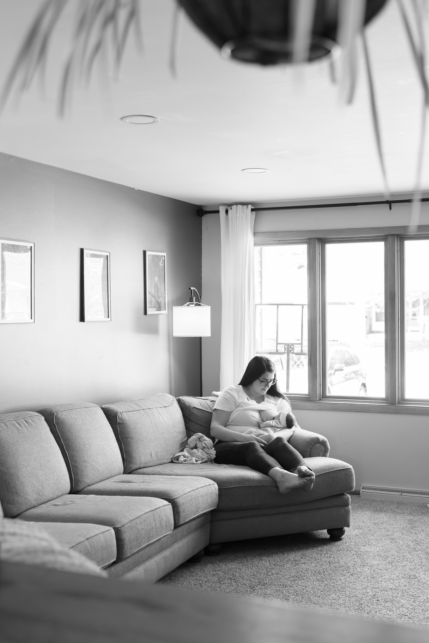 Mother feeding her newborn baby on the couch during newborn photography session in Oostburg, Wisconsin