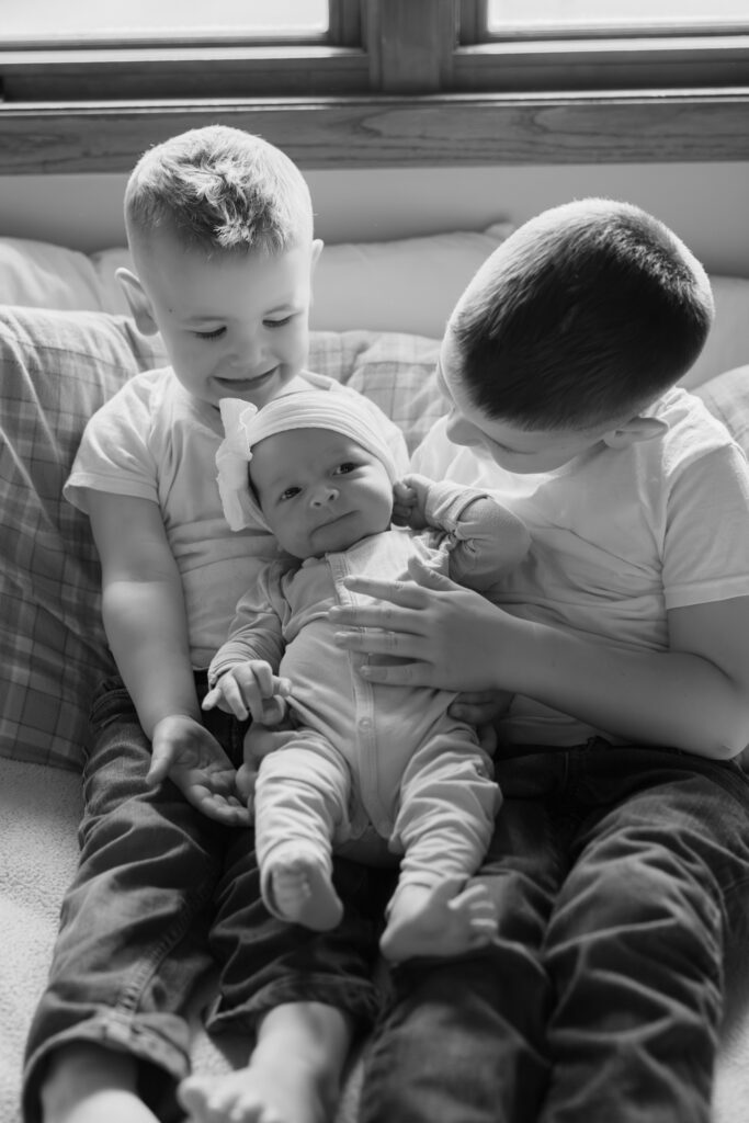 Two young boys holding their newborn baby sister during photography session at their home in Oostburg, Wisconsin