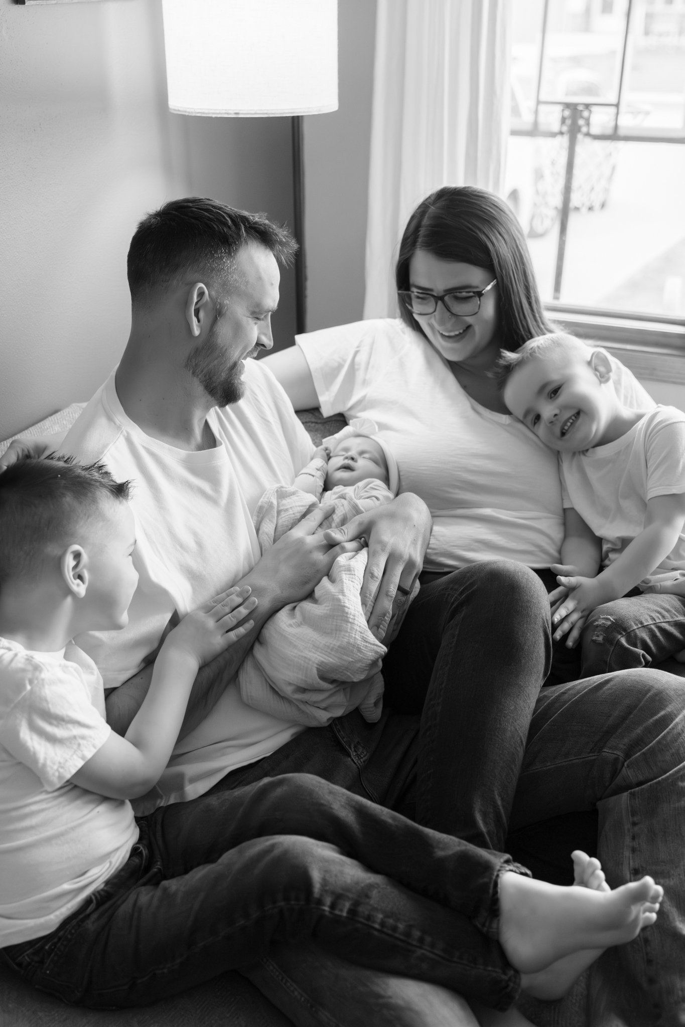 Family of five sitting on the couch and candidly interacting with eachother during in-home newborn session in Wisconsin