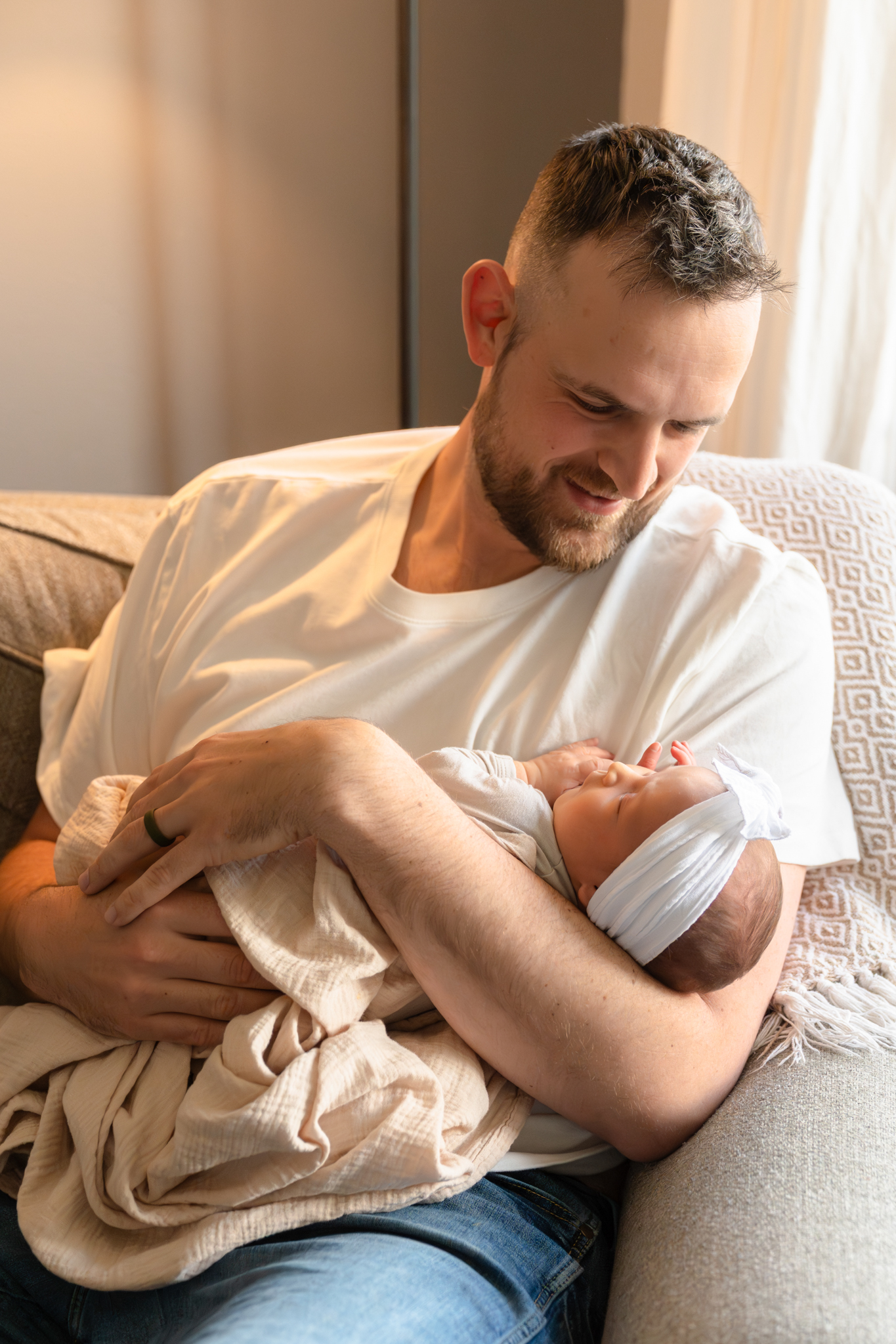 Father holding his newborn baby daughter while relaxing on the couch in their home
