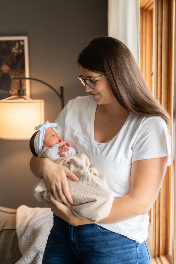 Mother holding her newborn baby in her arms during in home newborn photography session